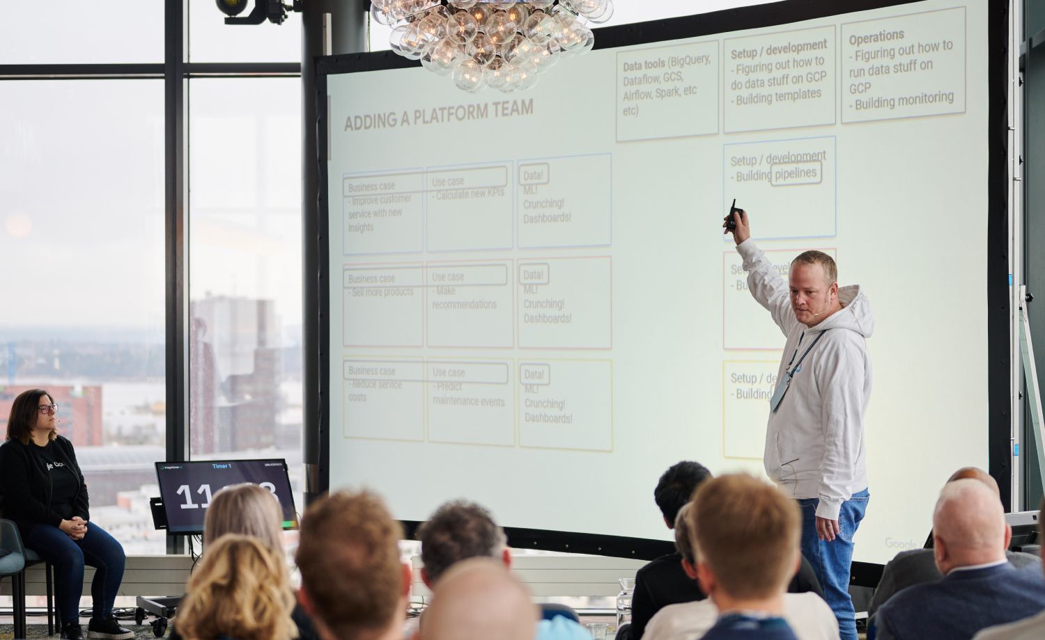 Mark Bryan presenting to an audience a slide with the heading "adding a platform team"